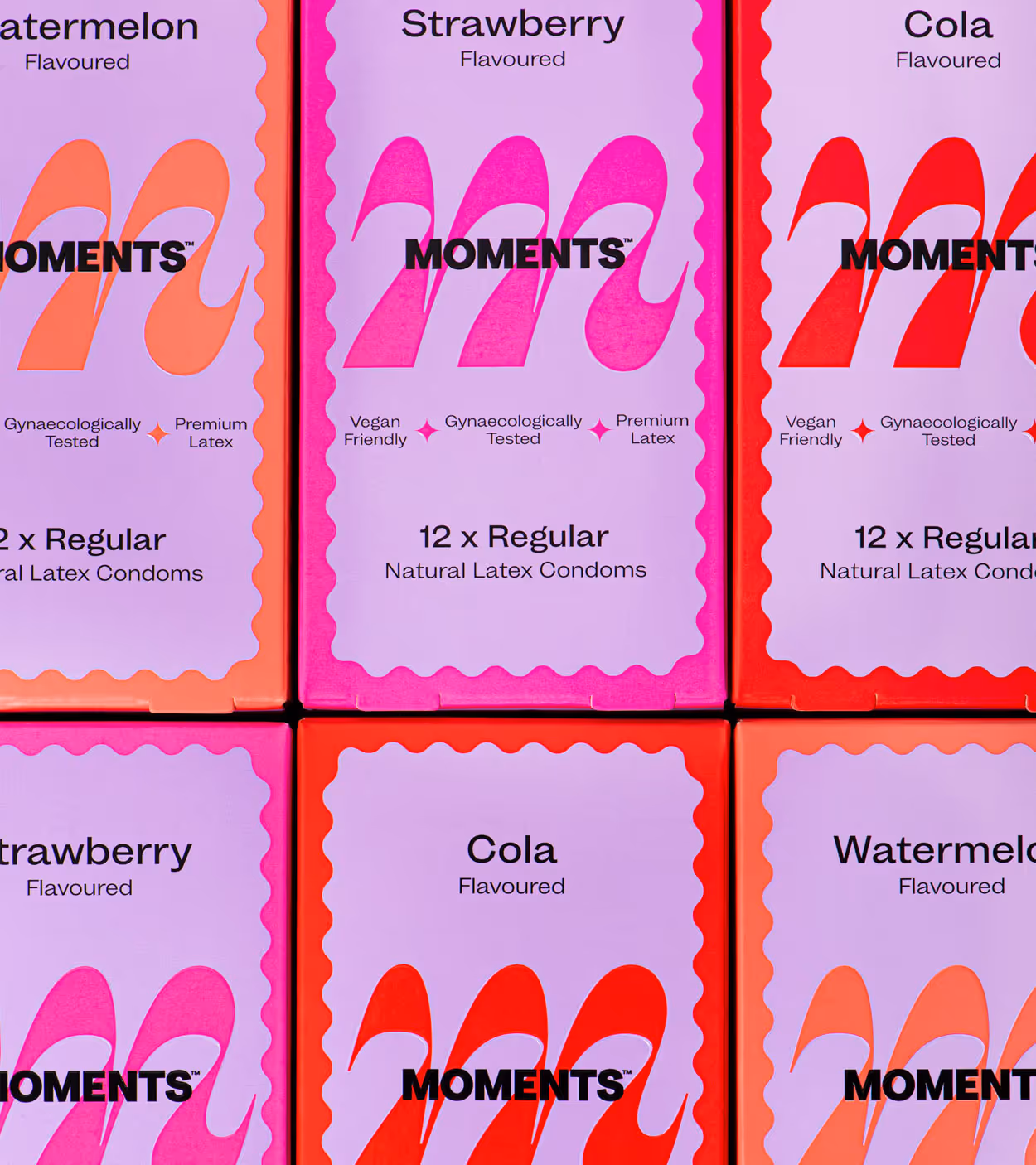 Six boxes of MOMENTS flavoured natural latex condoms in watermelon, strawberry, and cola flavors, with labels highlighting vegan friendliness, gynaecological testing, and premium latex.