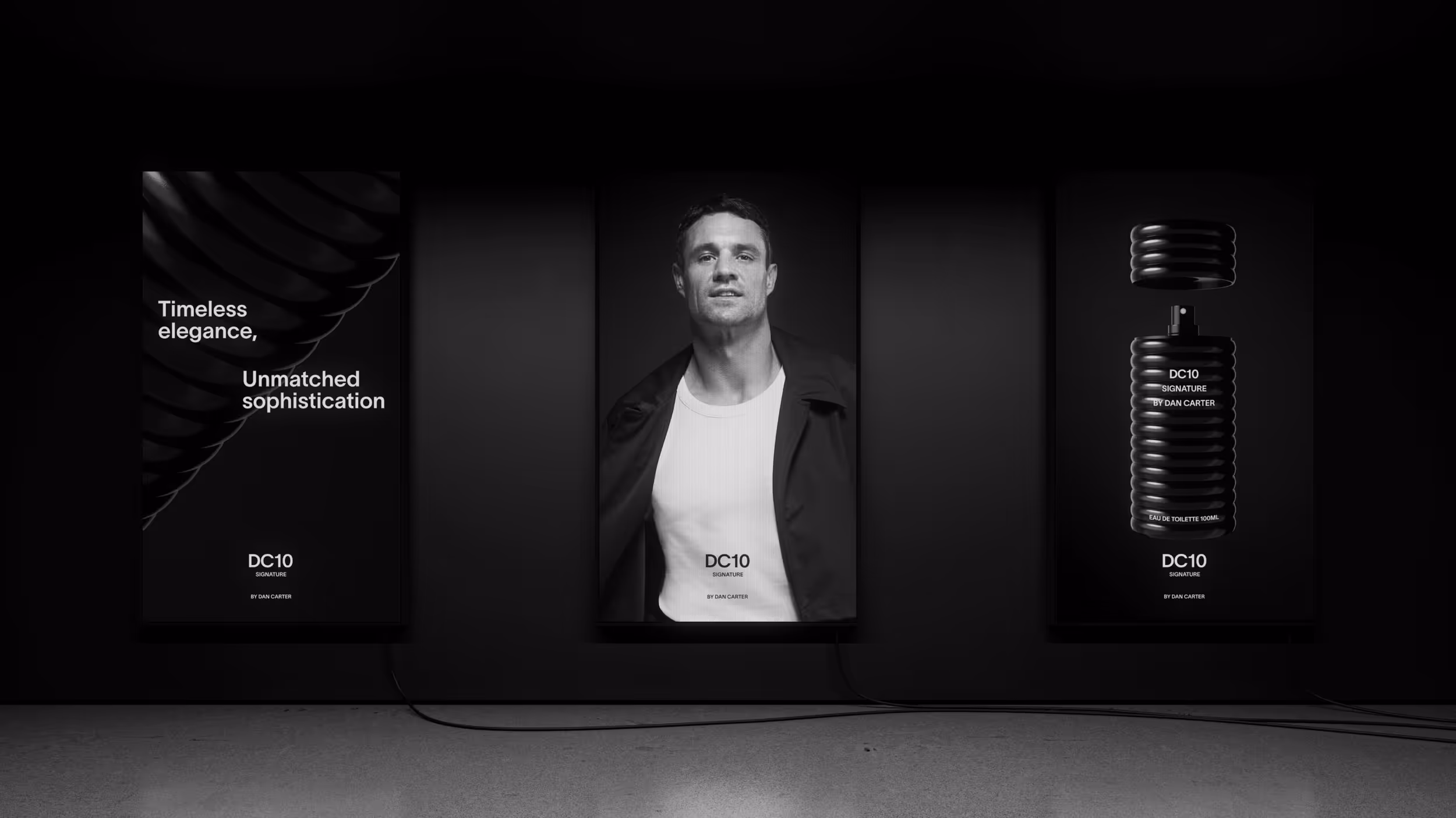 Three illuminated black panels on a dark wall displaying The DC10 Signature by Dan Carter: text with a spiral design, a man wearing a coat and white shirt, and a black perfume bottle.