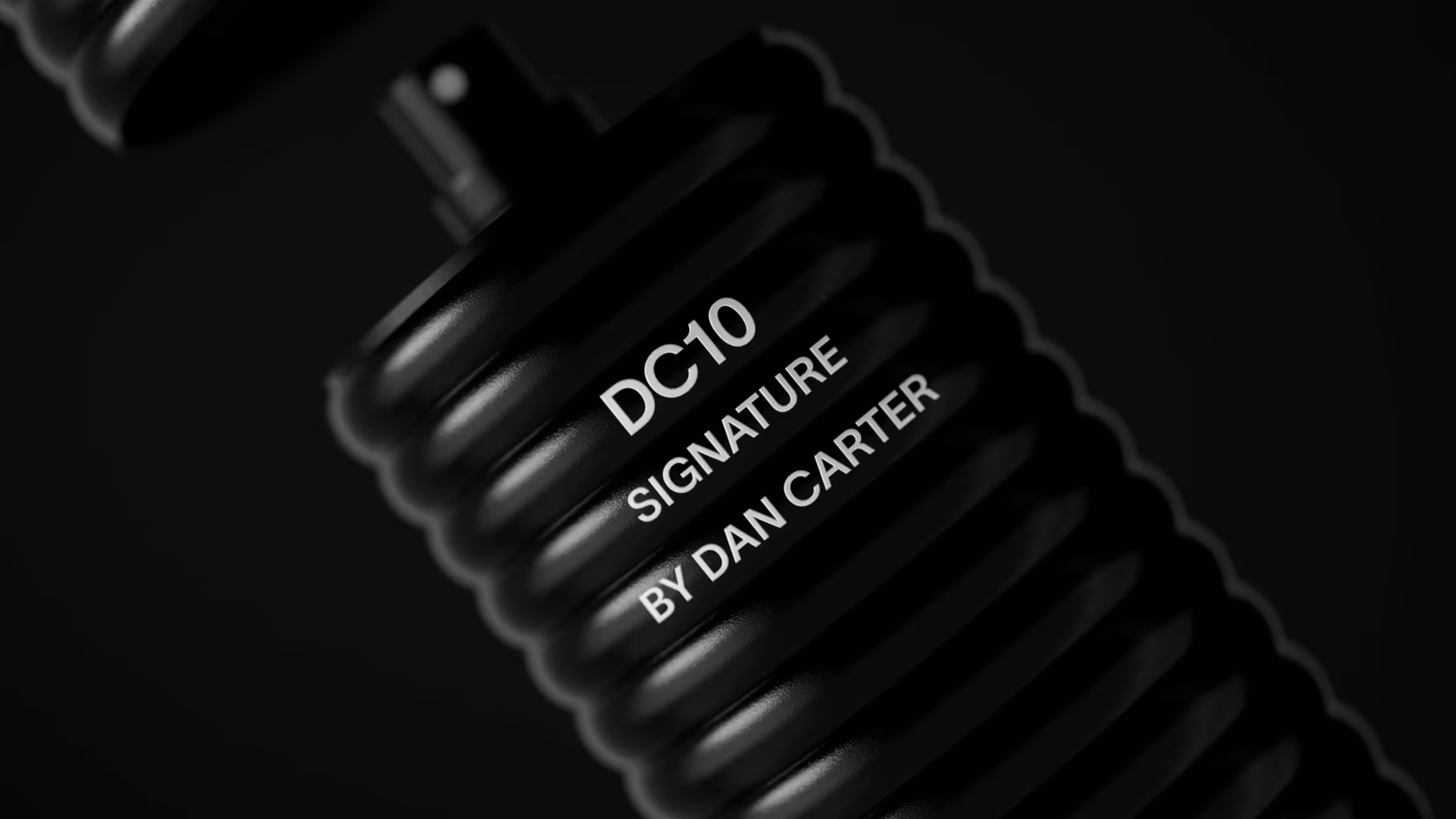 Close-up of a black ridged object with white text reading 'DC10 SIGNATURE BY DAN CARTER' on it.