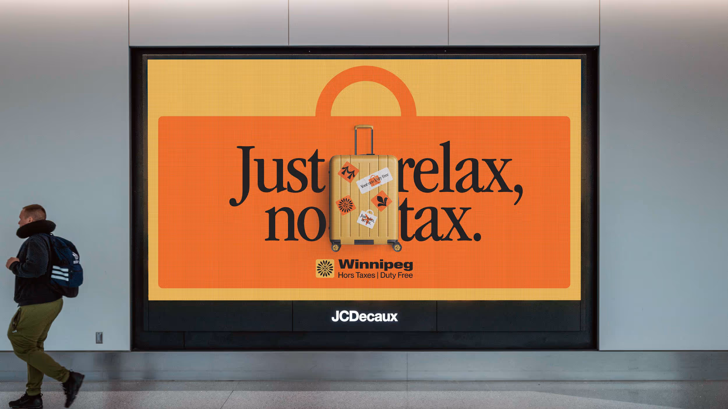 Airport advertisement with a yellow suitcase and orange luggage tag stating 'Just relax, no tax.' promoting Winnipeg Duty Free shopping.