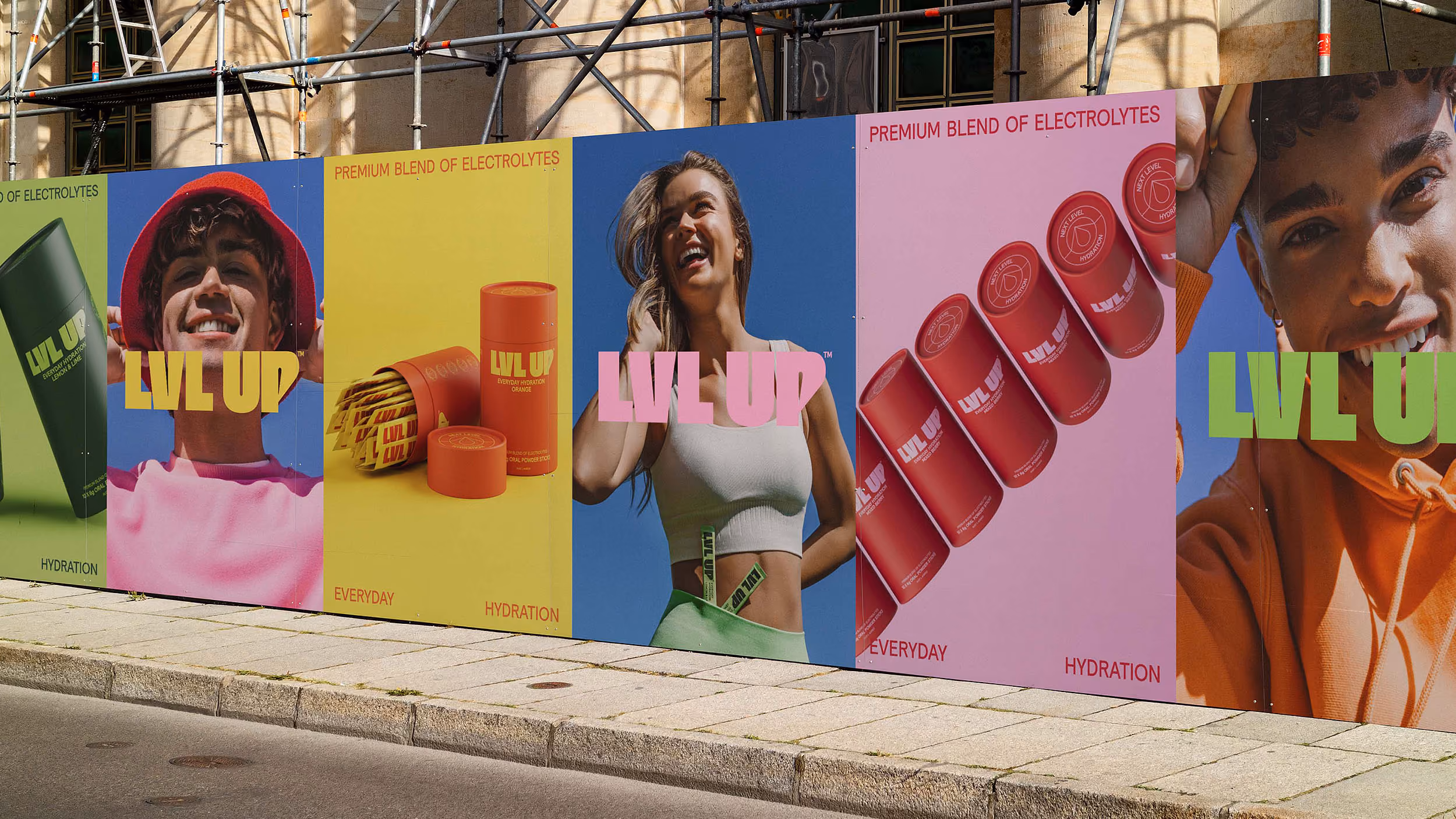 Outdoor colorful advertisement hoarding featuring young smiling people and hydration product packaging labeled LVL UP.