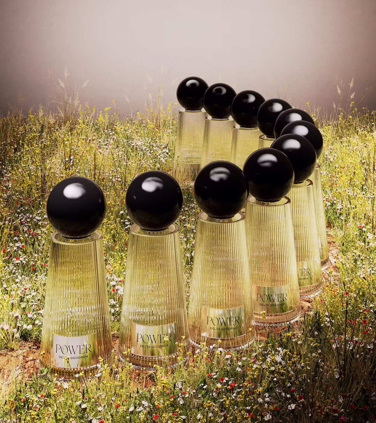 Ten tall, ribbed glass perfume bottles with black spherical caps arranged in a winding pattern on a field of wildflowers.