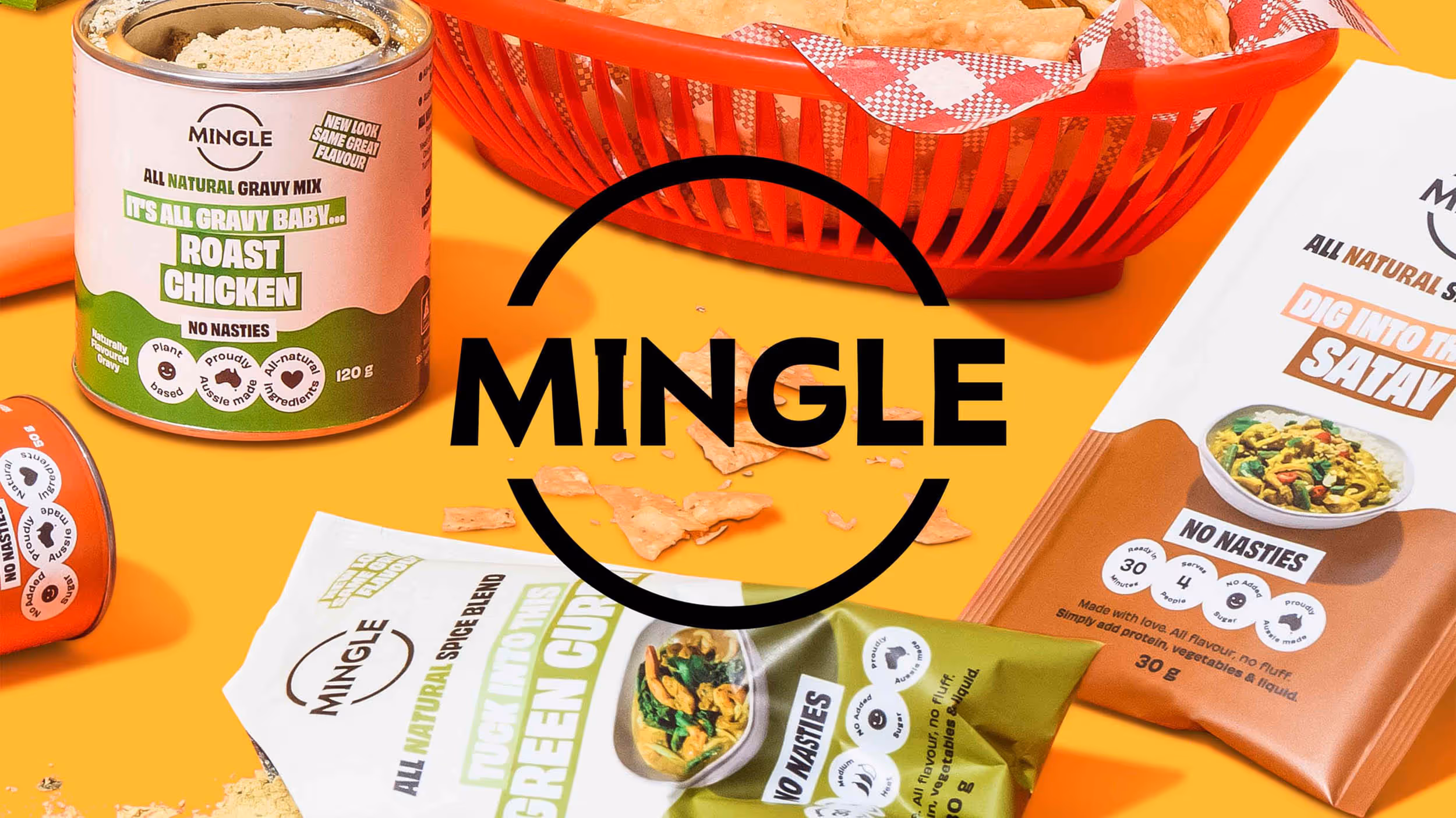 Mingle brand packaging for all-natural gravy mix and spice blends including roast chicken, satay, and green curry, with a basket of chips on an orange background.