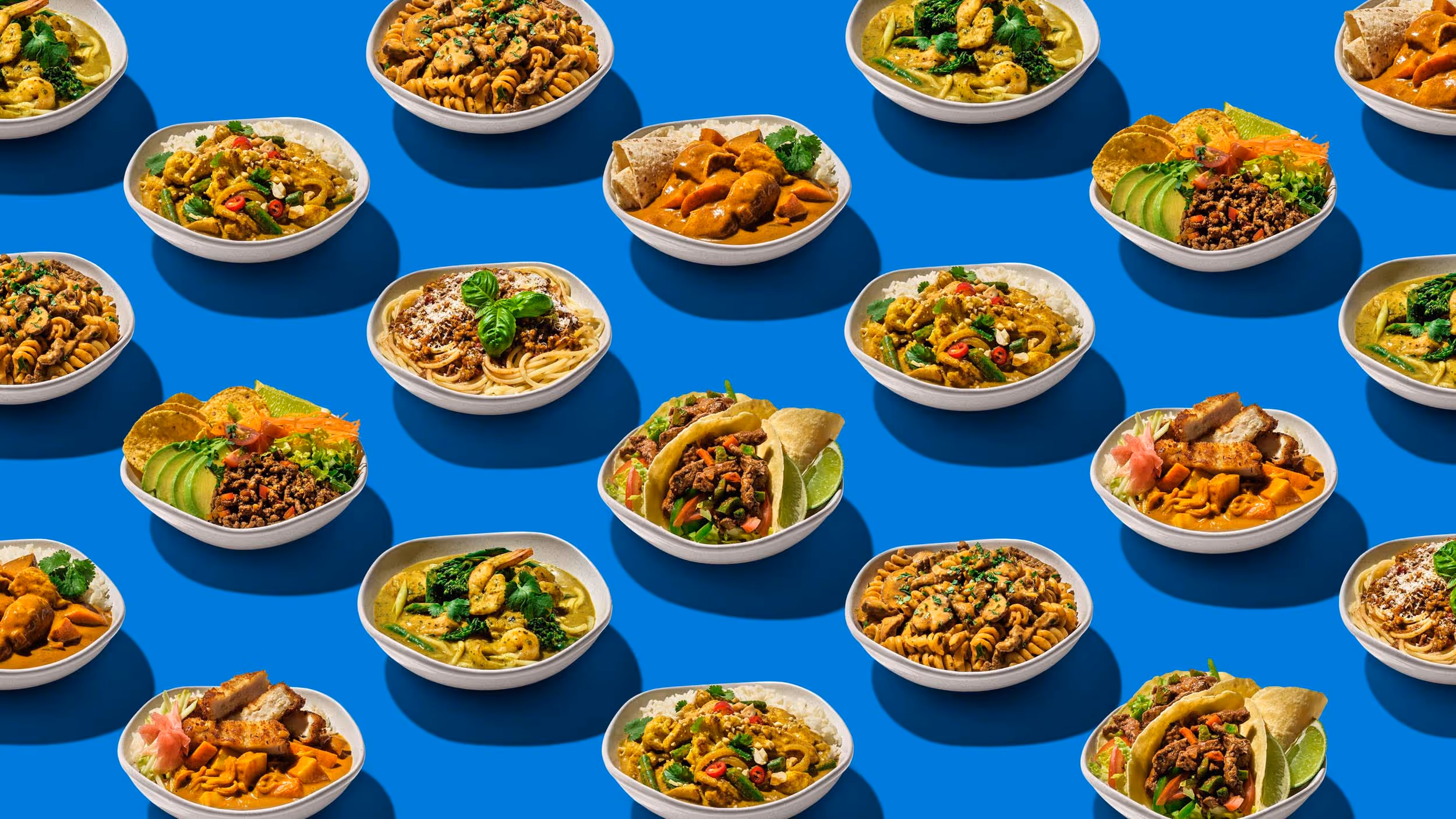 Assorted bowls of diverse dishes including tacos, pasta, curry, and rice meals on a blue background.