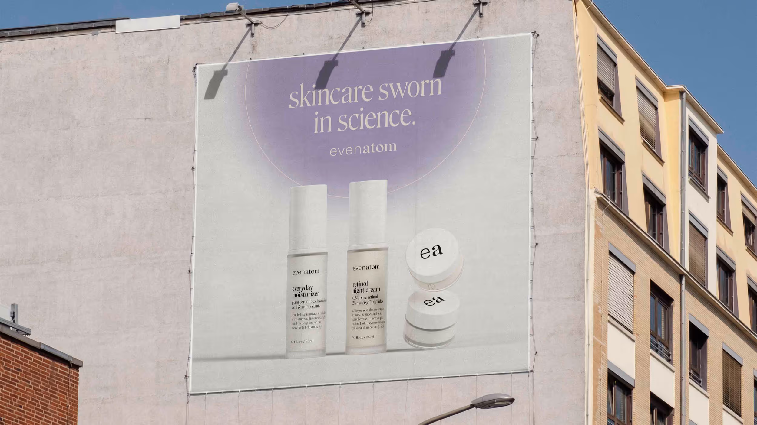 Outdoor billboard on a building wall featuring Evenatom skincare products with text 'skincare sworn in science.' and images of moisturizer, retinol cream, and jars.