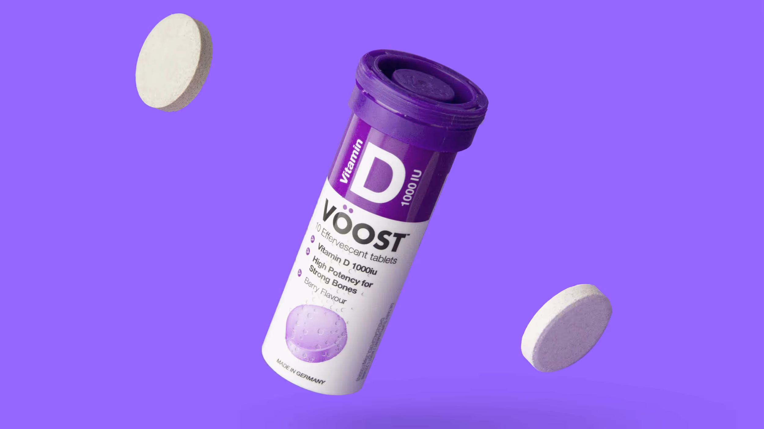 Purple and white tube of Voost Vitamin D 1000 IU effervescent tablets with two tablets floating on a purple background.