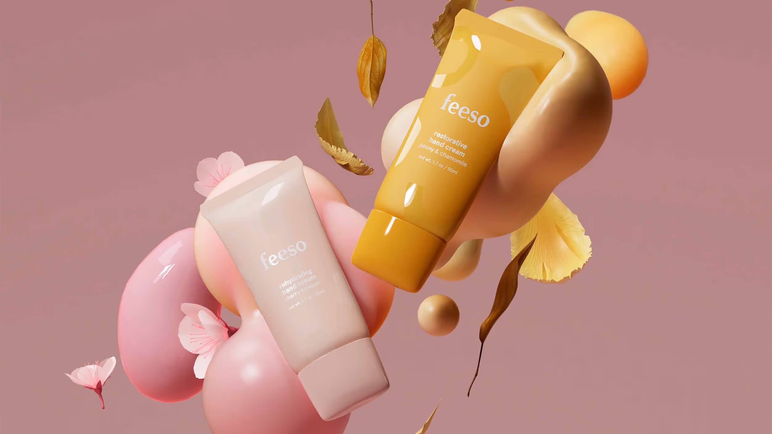 Two tubes of Feeso hand cream, one pink labeled rehydrating cherry blossom and one yellow labeled restorative peony & chamomile, surrounded by floating petals and abstract shapes on a mauve background.