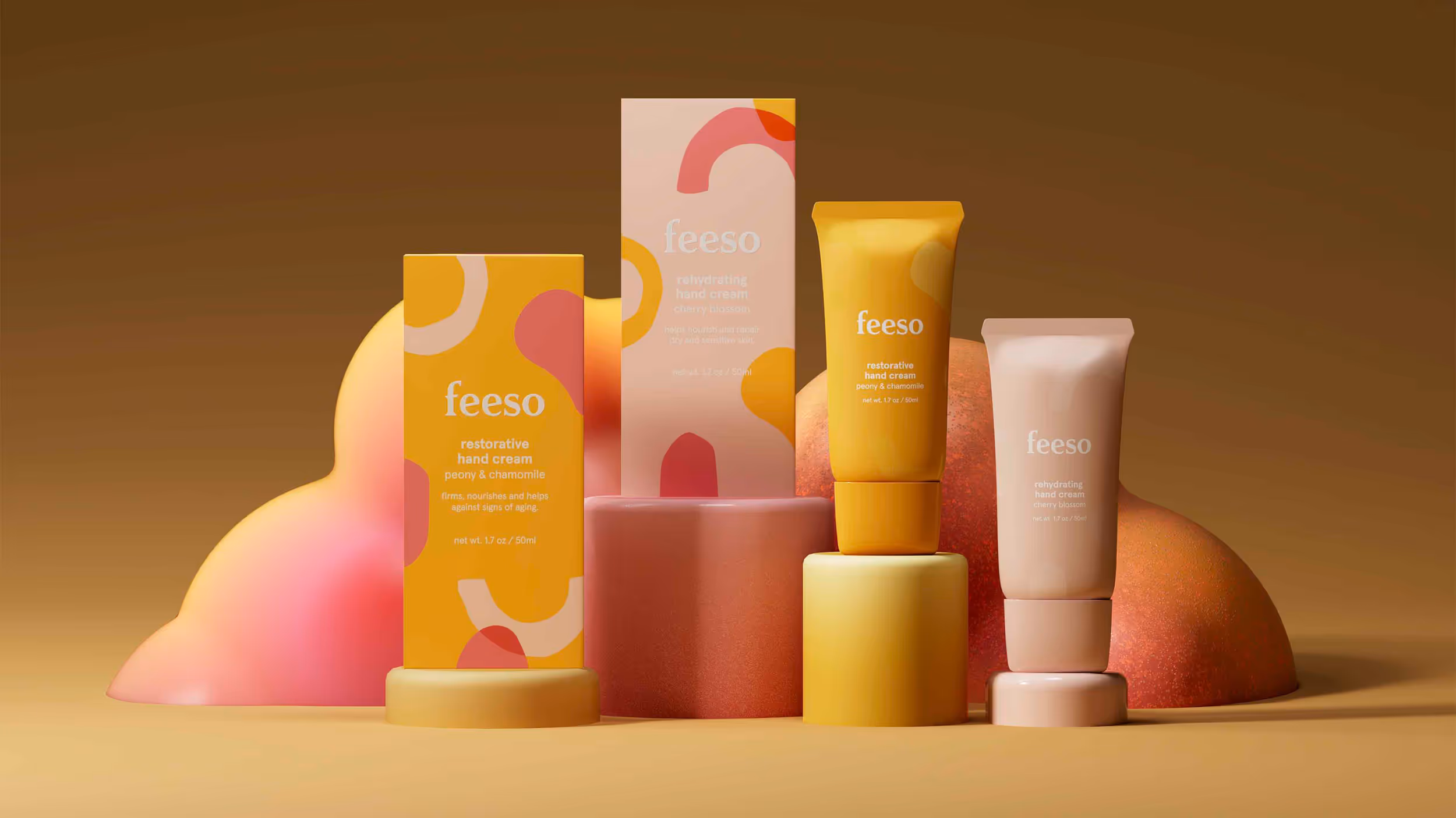 Two tubes and two boxes of Feeso hand creams in yellow and pink tones arranged on colorful pedestal shapes with abstract curved design in the background.