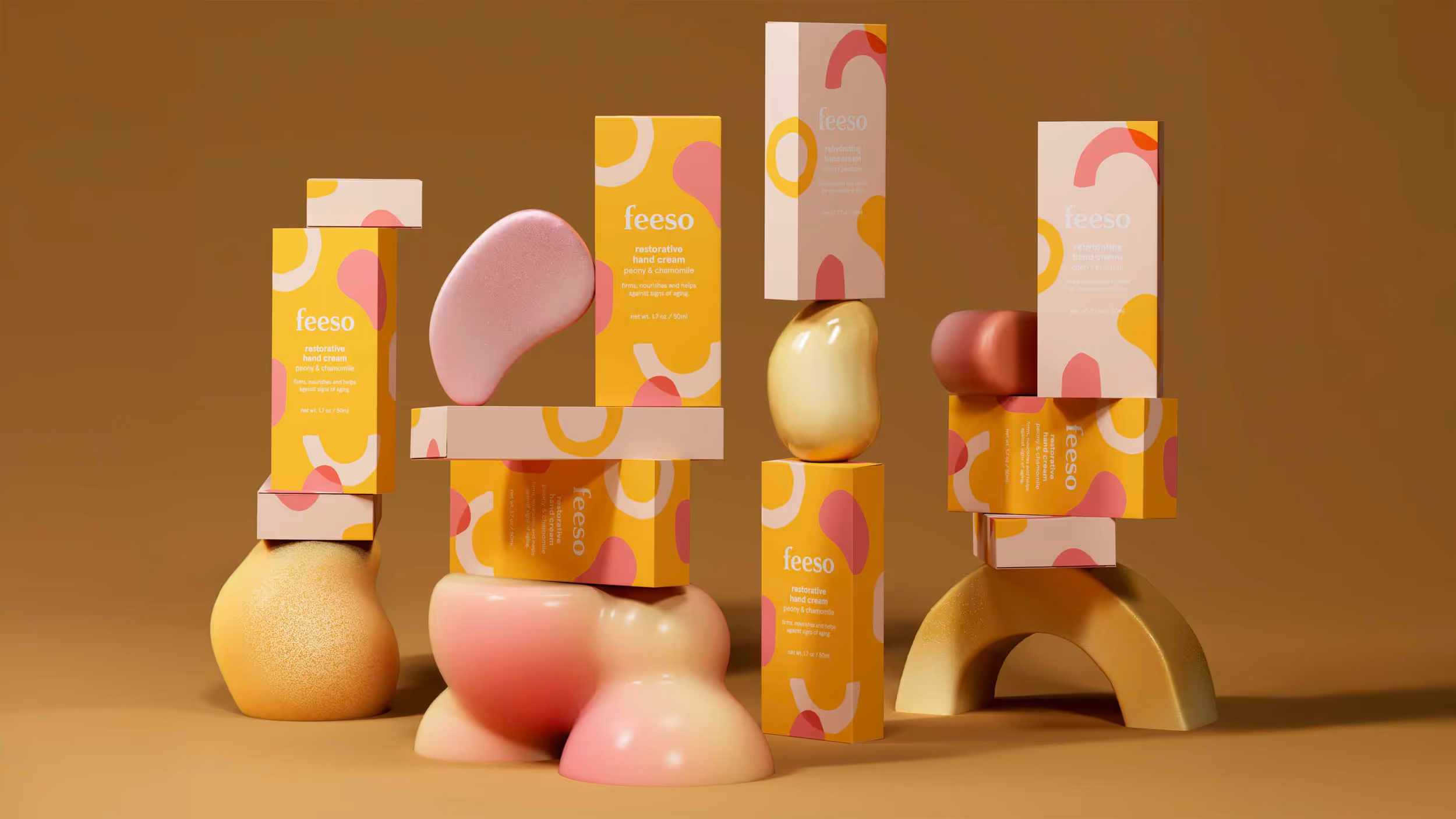 Stacked yellow and pink feeso hand cream boxes balanced on abstract, organic-shaped colorful forms against a brown background.