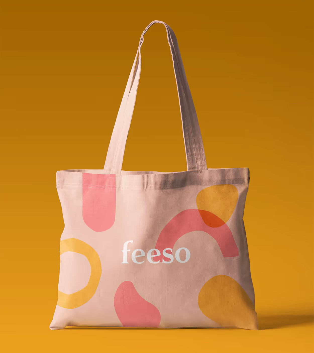 Beige tote bag with abstract pink and yellow shapes and the word 'feeso' printed in white.