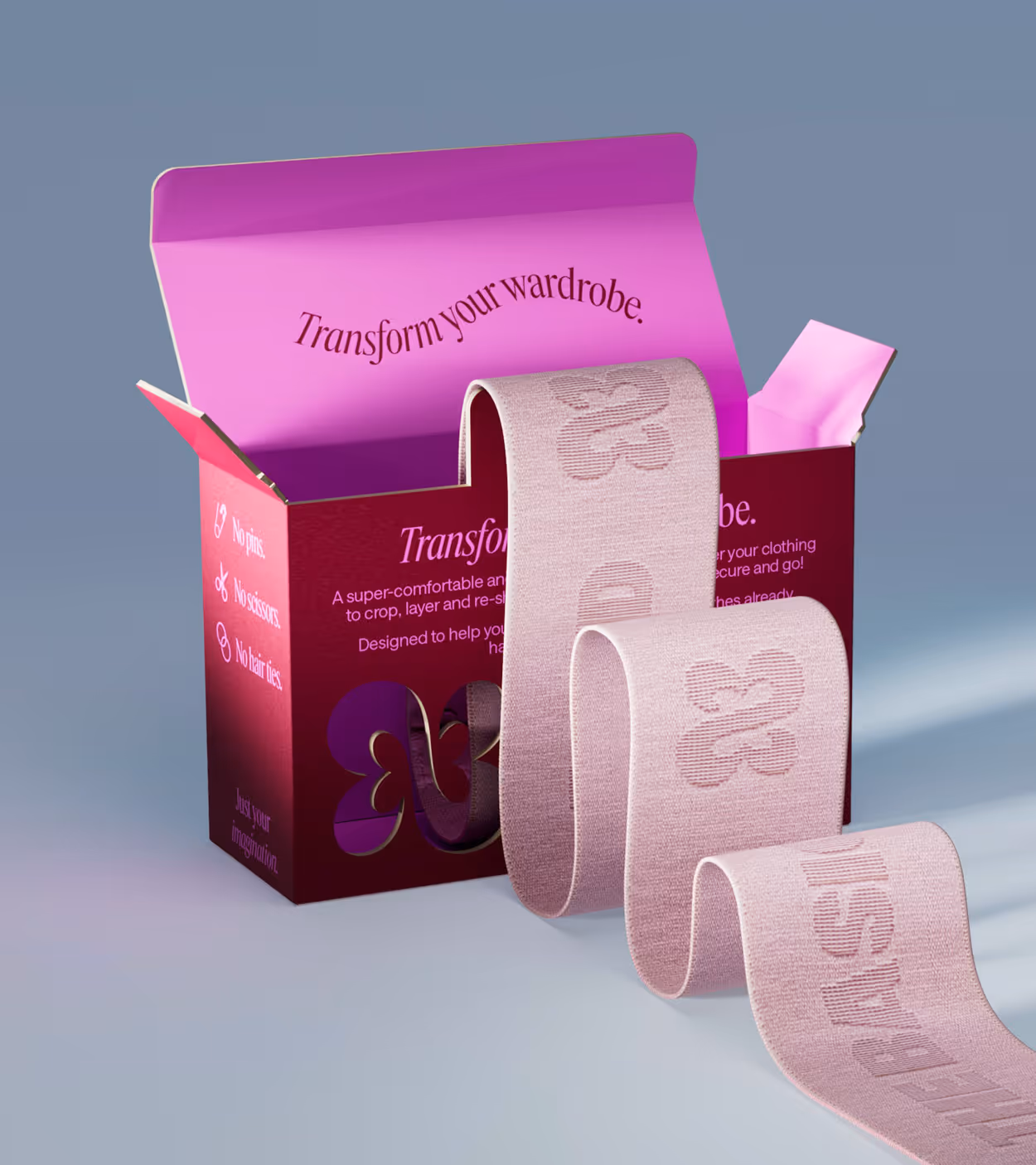 Open purple and pink box with 'Transform your wardrobe.' text and a long pink fabric band with floral and text patterns extending from it.