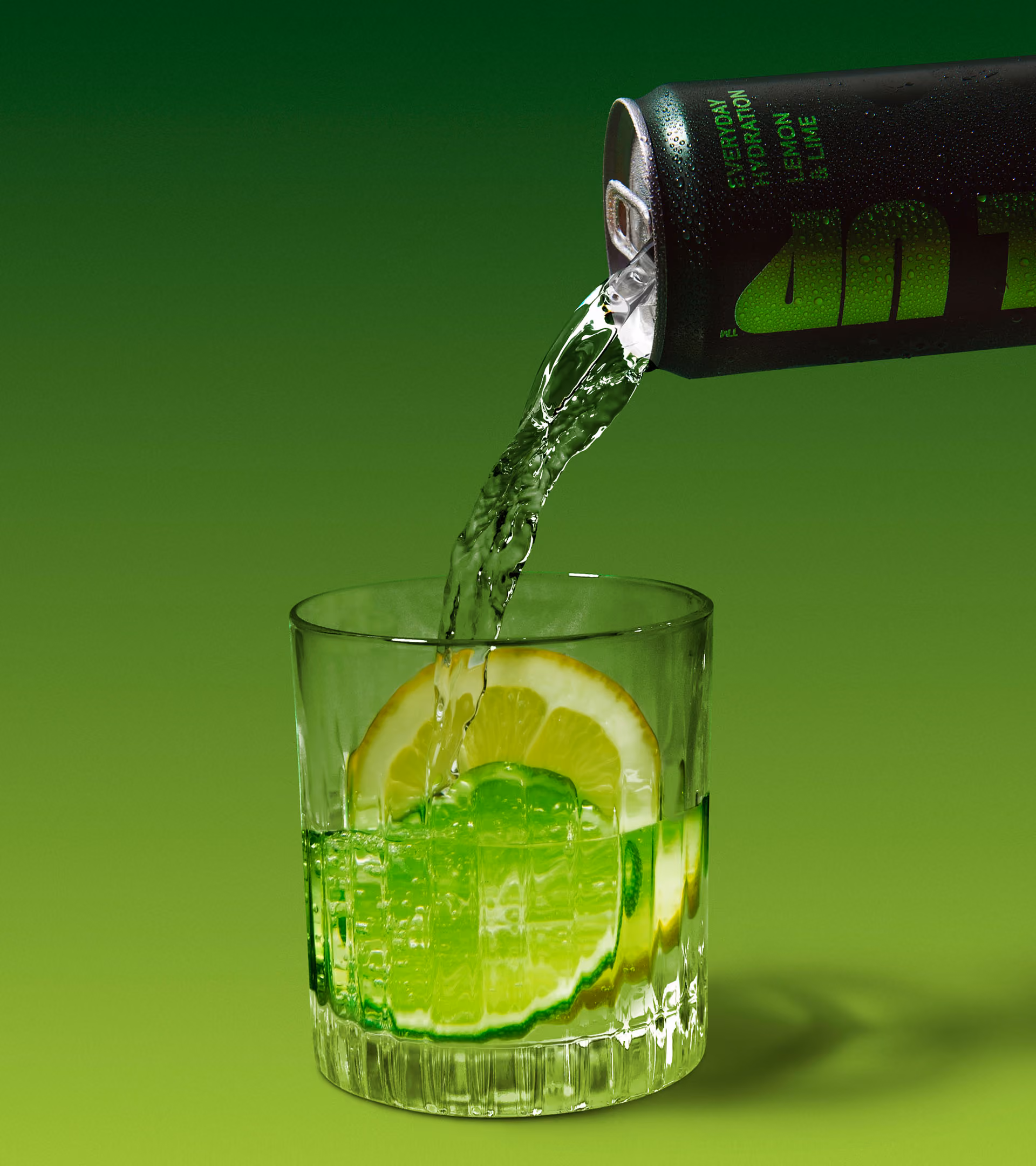 A black can labeled 'Everyday Hydration Lemon & Lime' pouring a clear green liquid into a glass with lemon and lime slices.