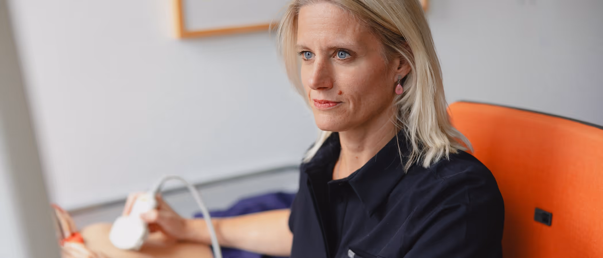 Frau mit blonden Haaren führt einen Ultraschall bei einer Patientin durch.
