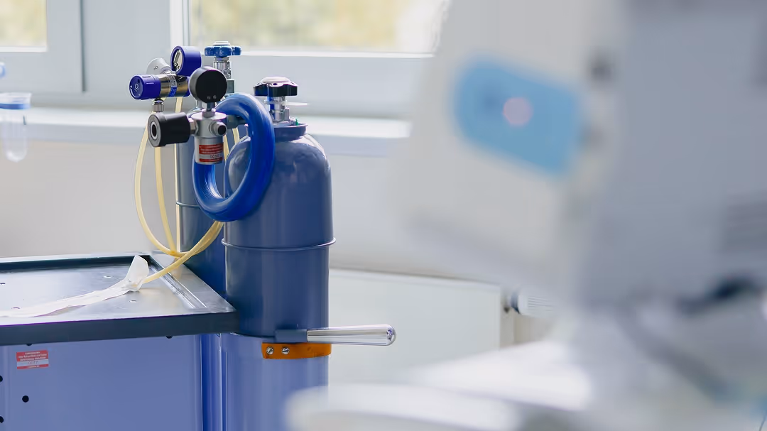 Medizinische Sauerstoffflaschen in einem hellen Raum neben einem medizinischen Gerät.