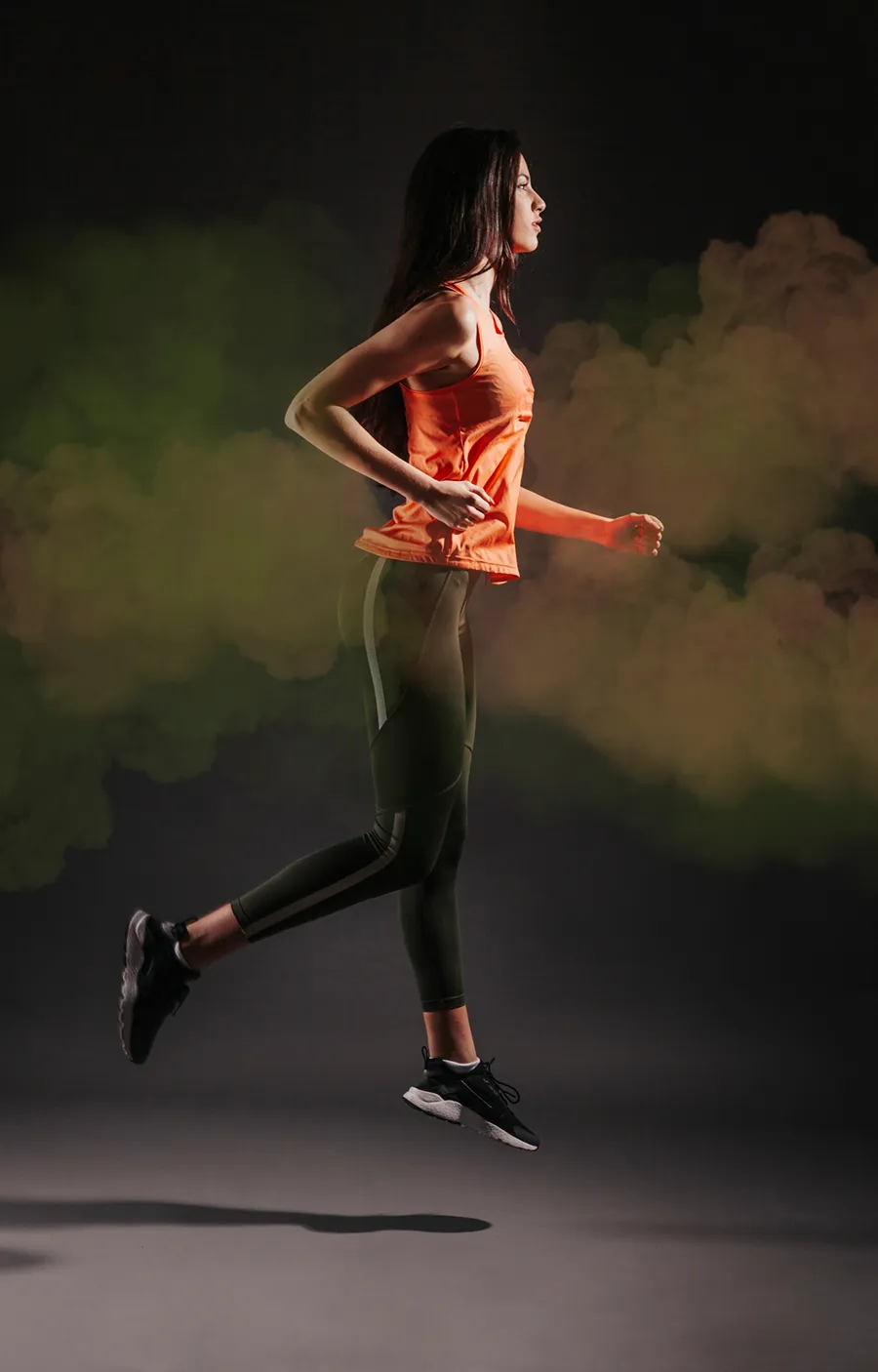 Female athlete running with colorful smoke background.
