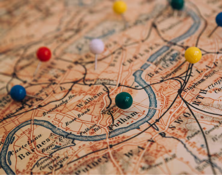 Close-up of an old map with multicolored pins marking locations along a river.
