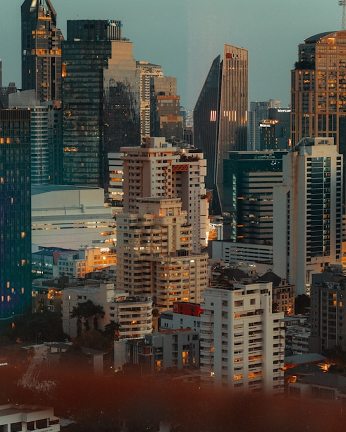 Cityscape of densely packed high-rise buildings at dusk with illuminated windows.