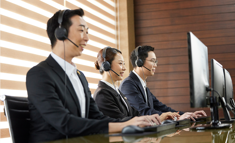 Three customer service representatives wearing headsets and typing on keyboards while looking at computer monitors.