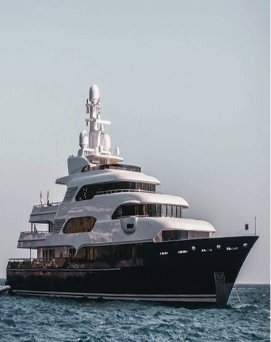 Large luxury yacht with multiple decks floating on calm ocean water under a clear sky.