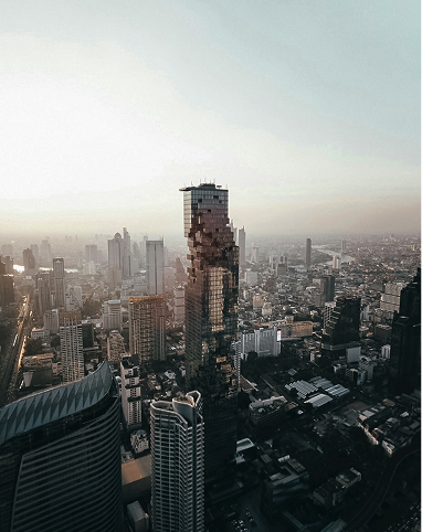 Aerial view of a cityscape featuring the pixelated design of the MahaNakhon skyscraper during sunset.