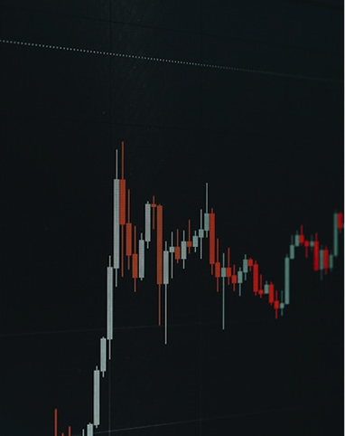 Close-up of a candlestick chart with red and green bars on a dark background, showing financial market data.