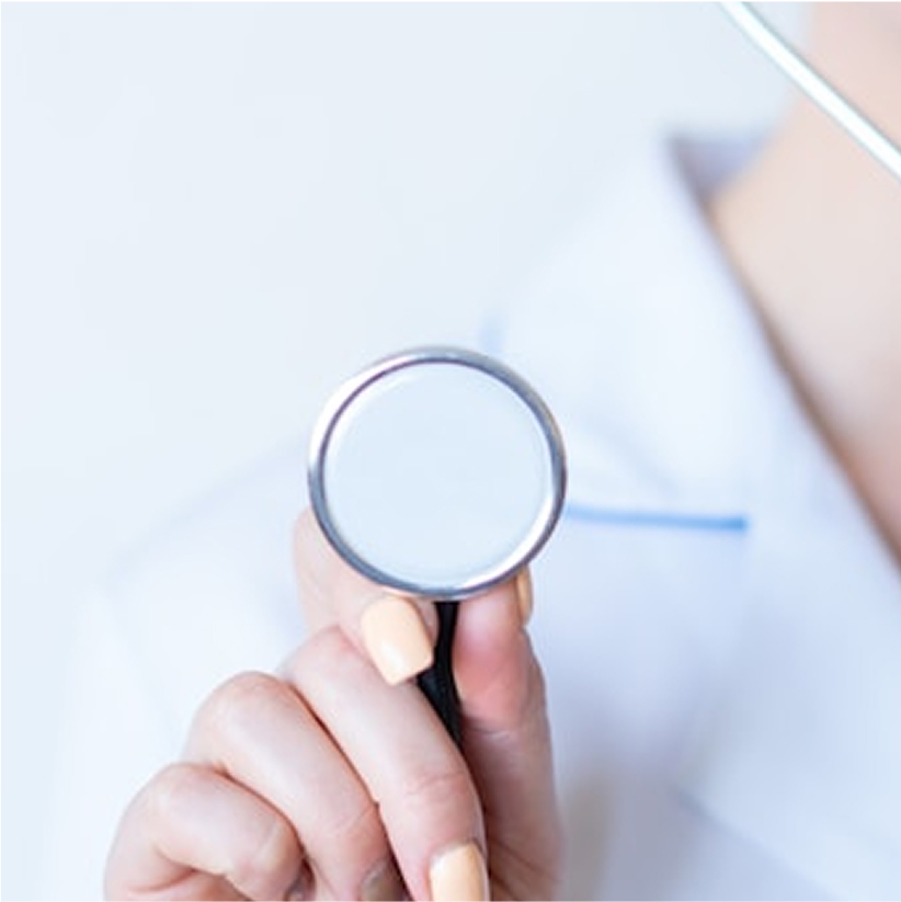 Close-up of a hand holding a stethoscope against a blurred white coat background.