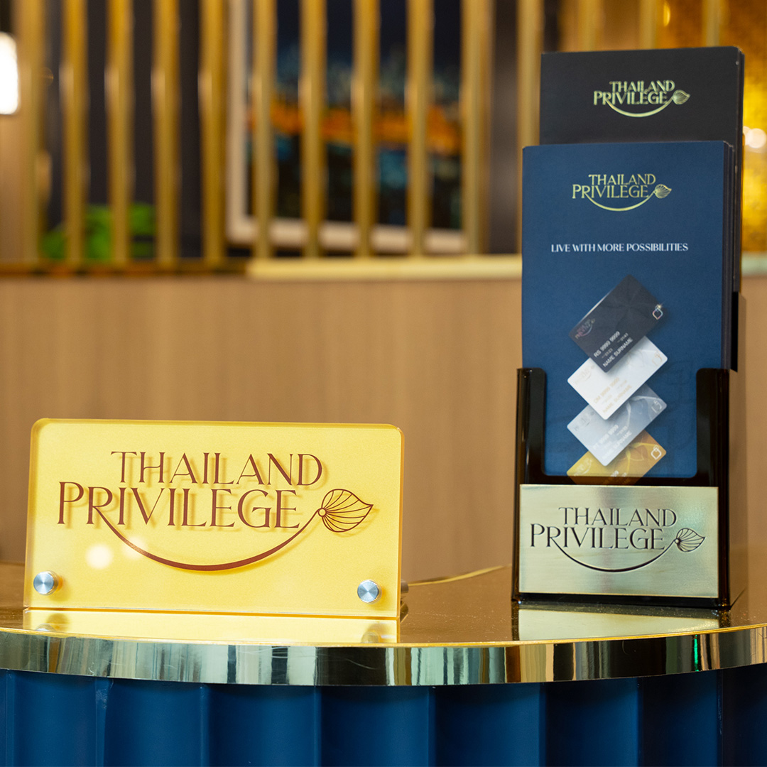 Yellow sign and brochure holder displaying the Thailand Privilege logo on a polished counter.