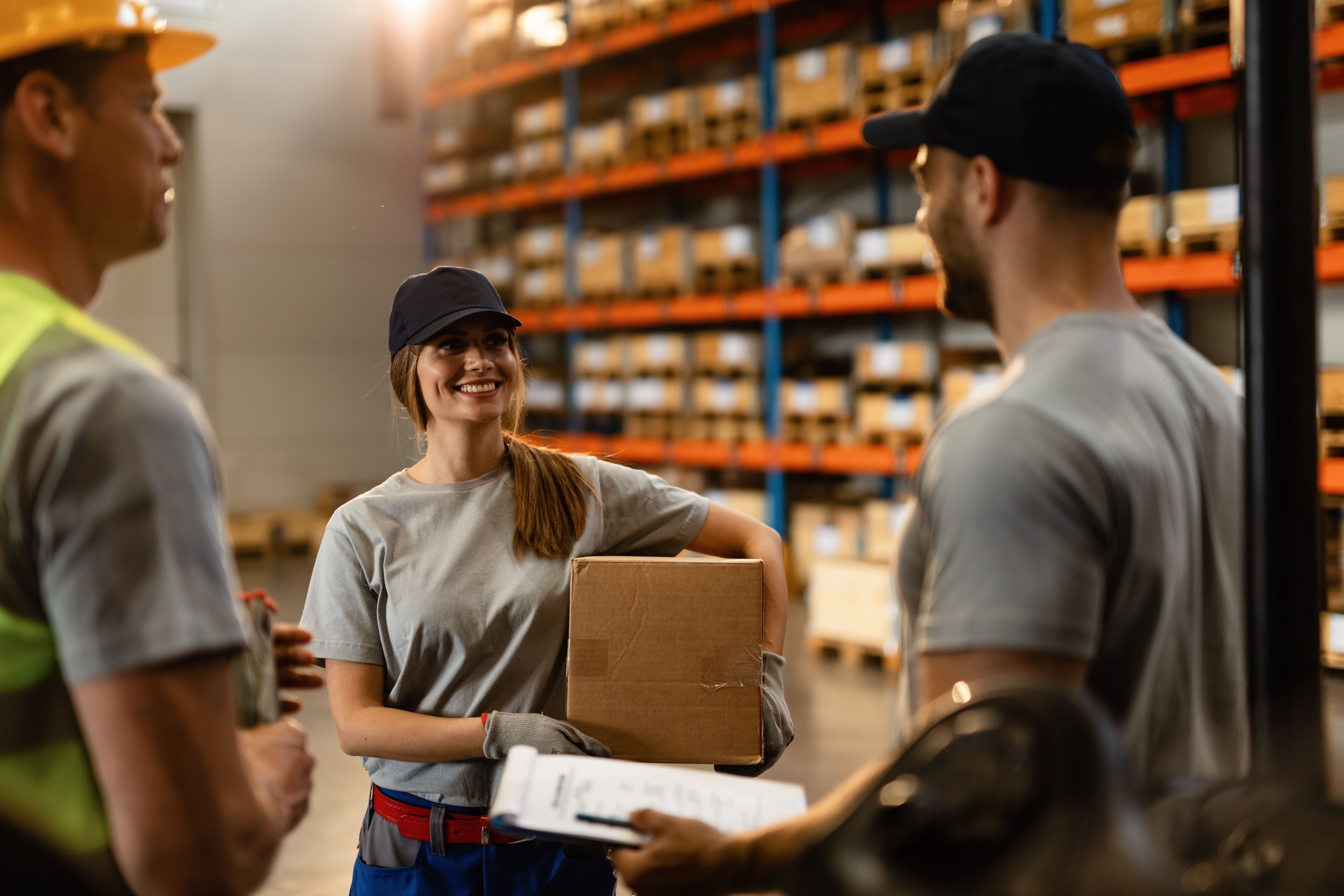 happy female warehouse worker talking with her coworkers