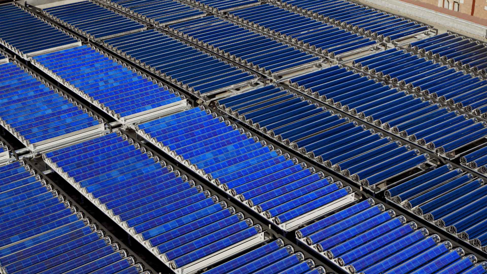 Aerial view of multiple rows of solar panels, featuring blue cells arranged on a rooftop for solar energy capture.