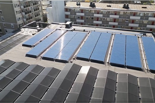 Rooftop with solar panels and buildings in the background under clear daylight.