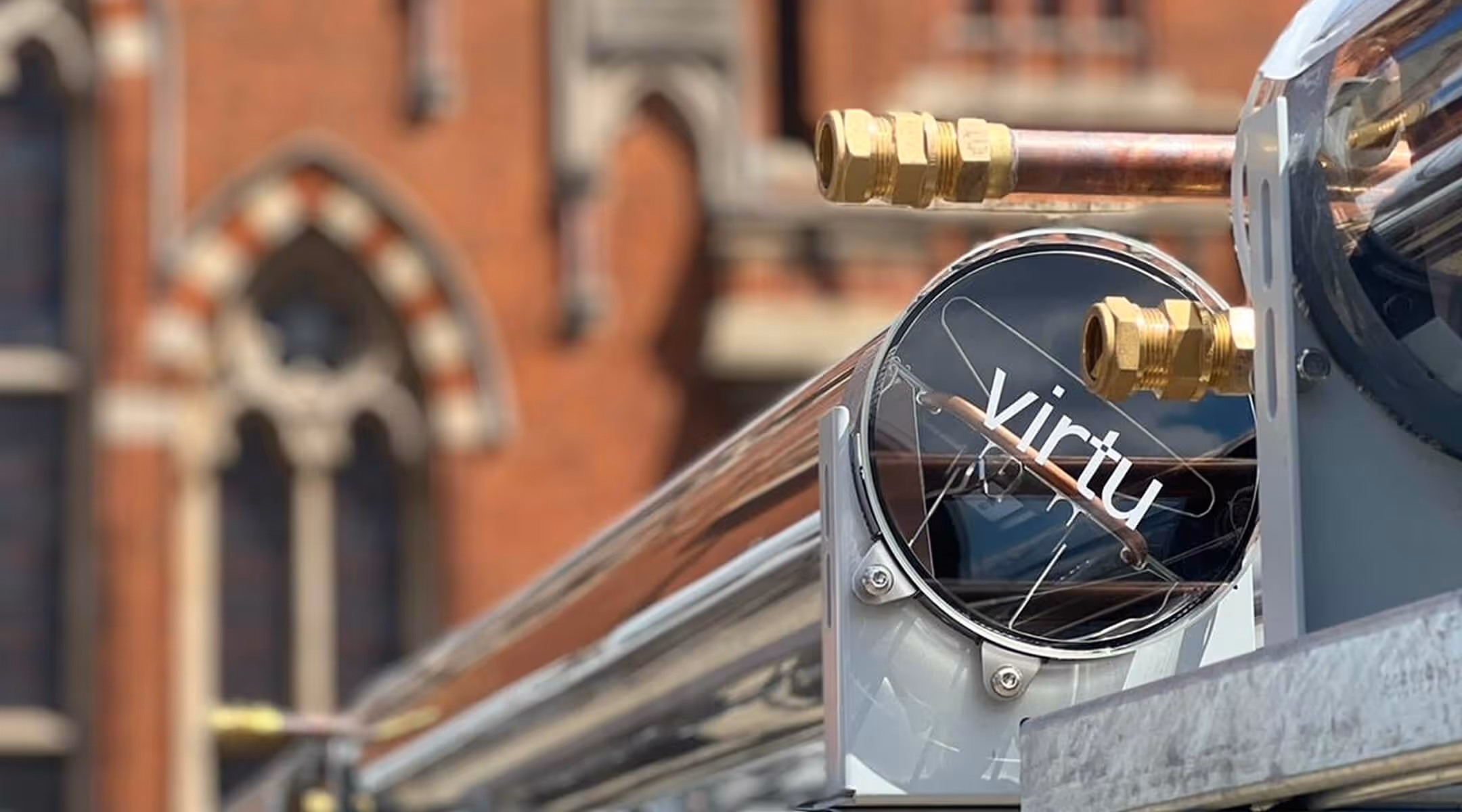 Close-up of a polished metal and glass panel labeled 'virtu' with brass fittings and copper tubing.