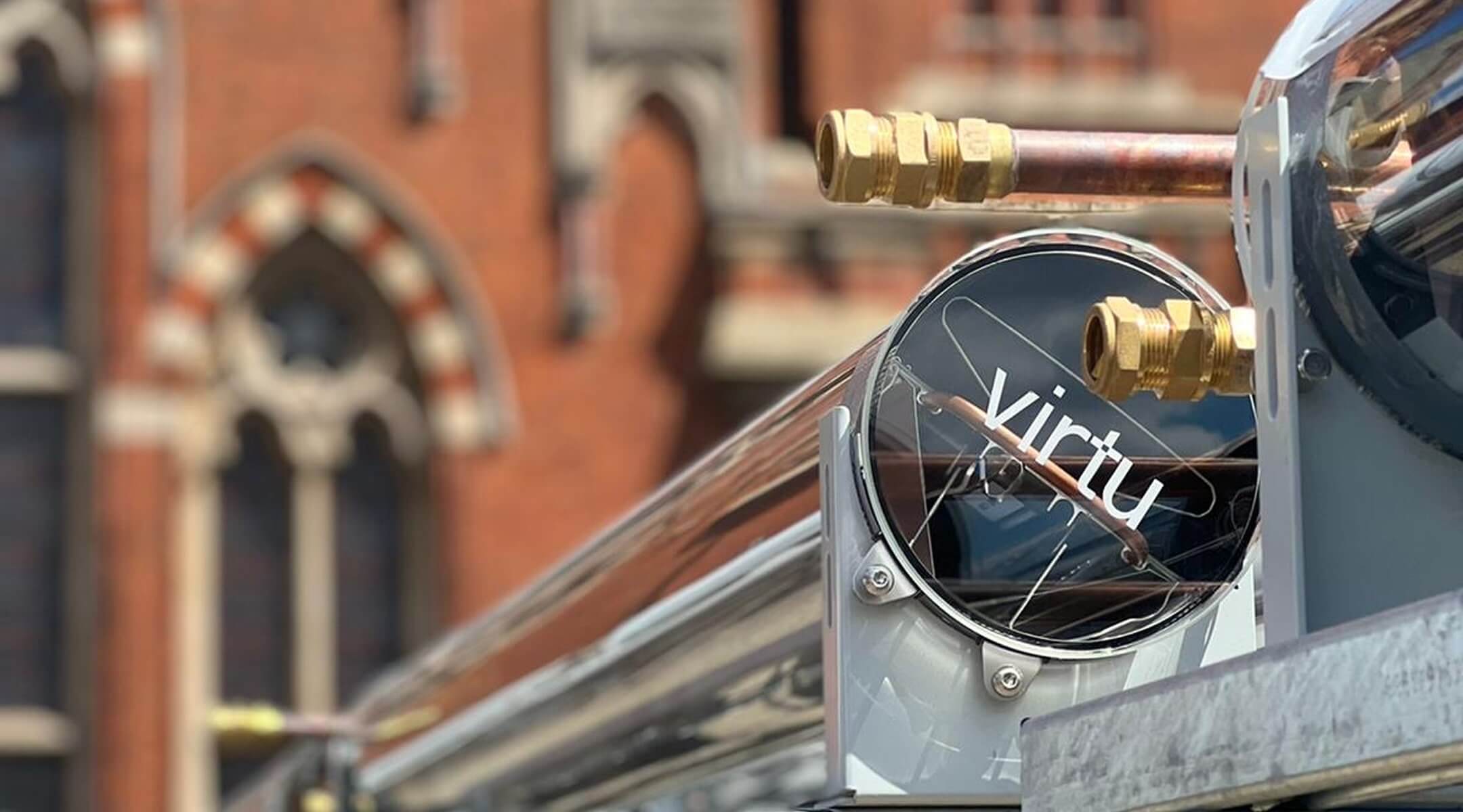 Close-up of a polished metal and glass panel labeled 'virtu' with brass fittings and copper tubing.