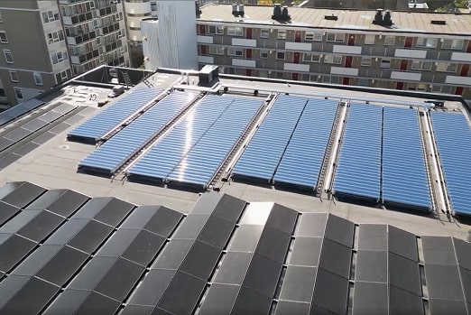 Solar panels installed on the rooftop of an urban building with other residential buildings in the background.
