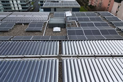 Techo cubierto con múltiples paneles solares y tubos solares térmicos en edificios de una zona urbana.