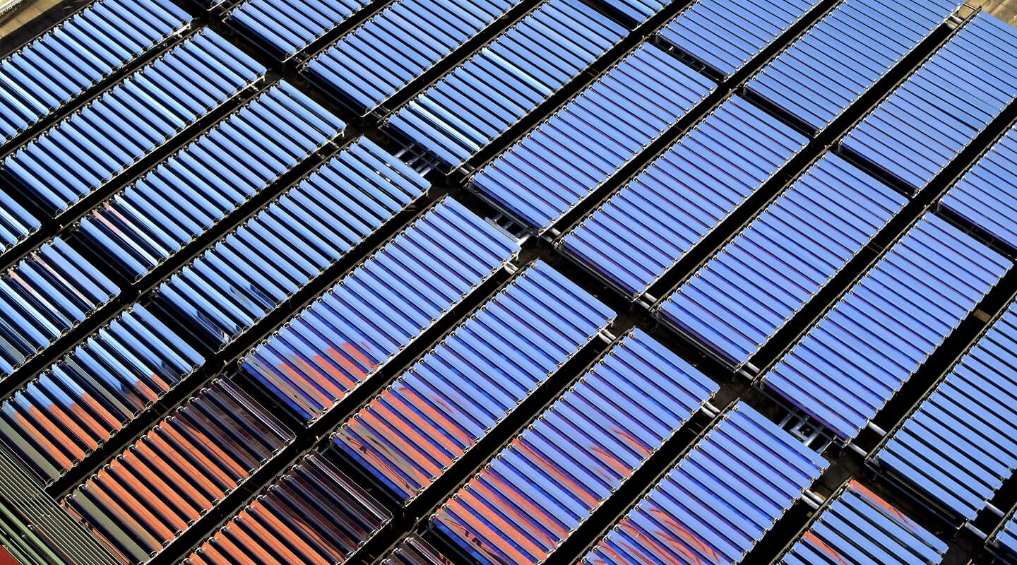 Rows of blue solar panels with orange reflections arranged in a geometric pattern.