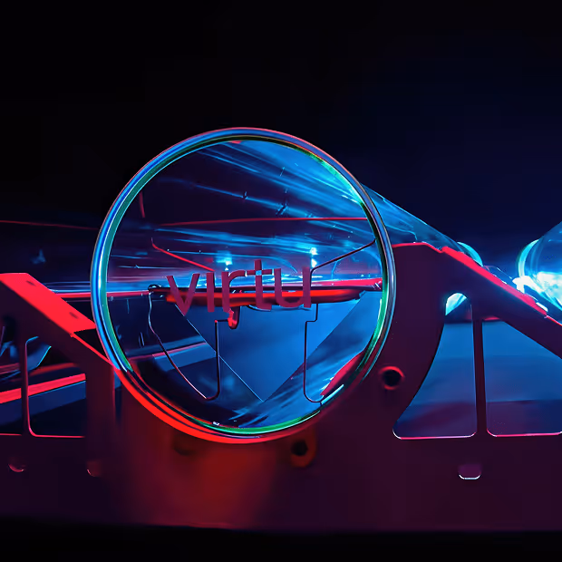 Close-up of a transparent optical prism and frame illuminated with blue and red light against a dark background.