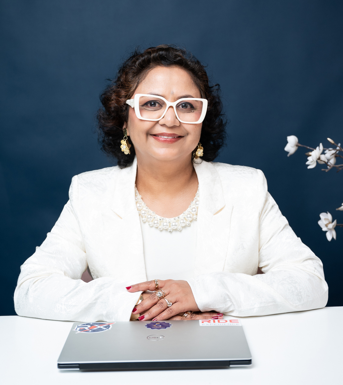 Sylvauraa founder seated portrait wearing white attire against a blue background