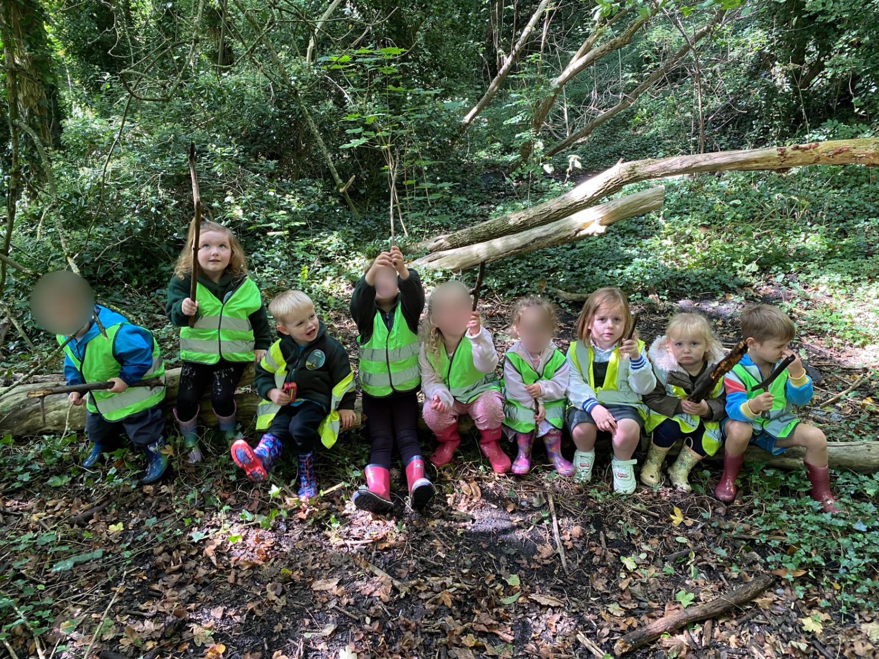Children playing alongside each other on a log (parallel play) in our outdoor setting