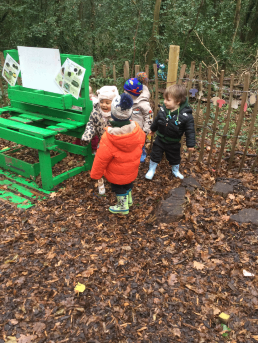 Children exploring the green outdoor structure at Woodlands Preschool Hemel