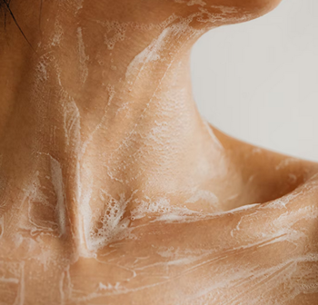 Close-up of a person's neck and shoulder with soap suds applied.