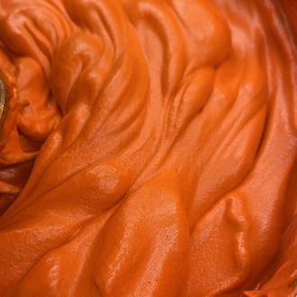 Close-up of smooth, creamy orange-colored mousse or frosting with soft swirls.