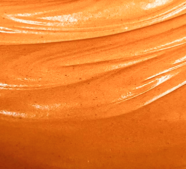 Close-up of smooth, glossy, orange-colored creamy substance with textured swirls.