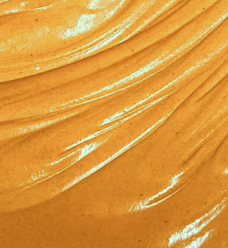 Close-up of smooth, glossy caramel-colored creamy texture with light reflections.