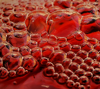 Close-up of red liquid with clusters of bubbles on the surface.