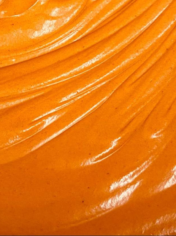 Smooth, creamy orange-colored sauce or dressing with visible swirls.