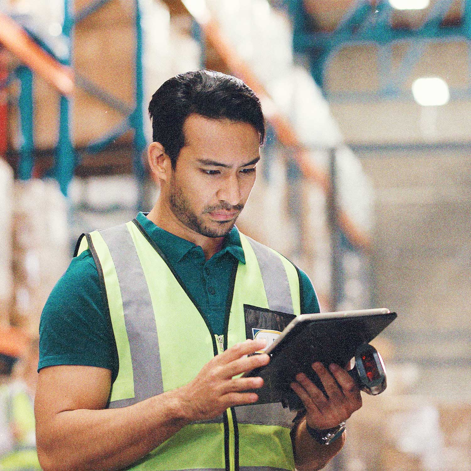 Warehouse worker in a high-visibility vest using a tablet for inventory management.