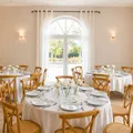 Elegant dining room with set round tables, wooden chairs, and large, bright patio door.