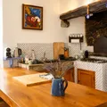Rustic kitchen with a large wooden counter, a kettle, a stone wall, and a colorful chalkboard.