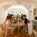Group of people sitting around a large wooden table in a bright arched room.