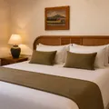 Room with double bed, green cushions, table lamp and wall chart.